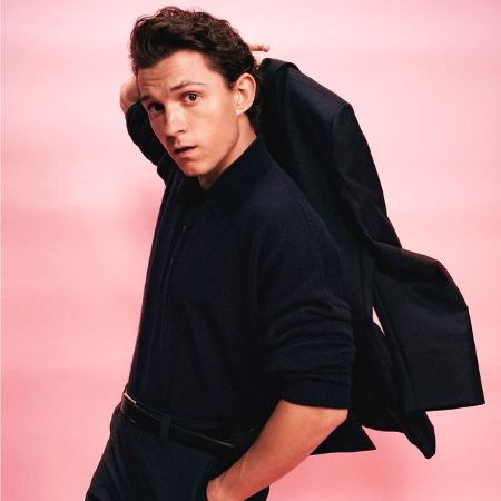 Tom Holland posing for a picture in a black suit